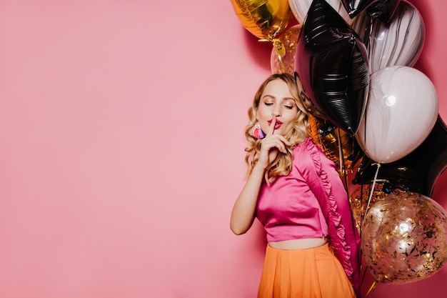 Mujer de cumpleaños elegante posando en la pared rosa