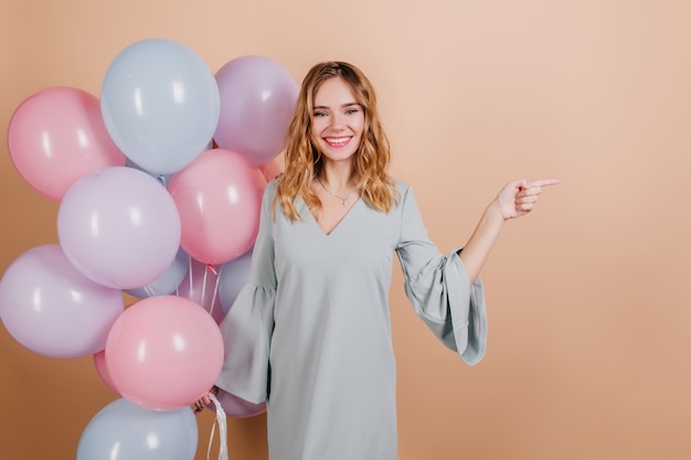 Mujer de cumpleaños maravillosa posando con una sonrisa y sosteniendo globos brillantes