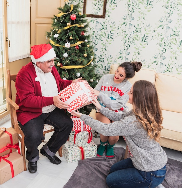 Mujer dando caja de regalo a anciano.