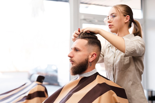 Mujer dando un corte de pelo a un cliente