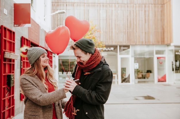 Mujer dando globos de corazón a novio sonriente