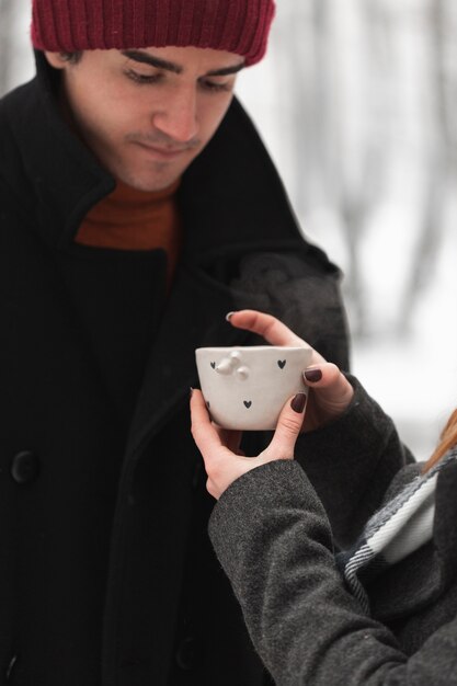 Mujer dando una taza de té caliente a su novio