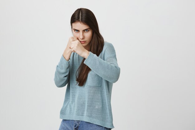 Mujer decidida seria de pie pose defensiva, boxeo