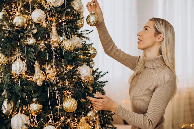 Mujer decorando el árbol de Navidad con juguetes
