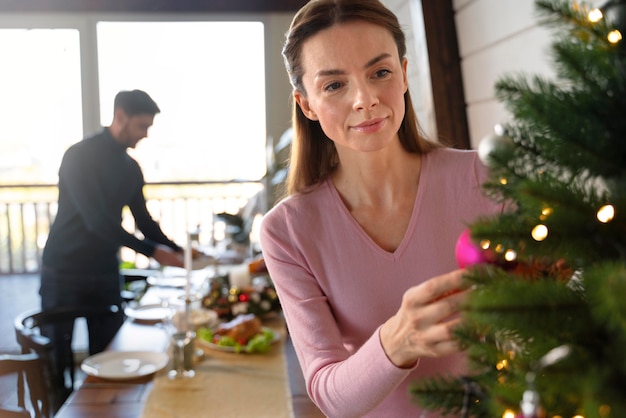 Mujer decorando el árbol de navidad junto a su marido