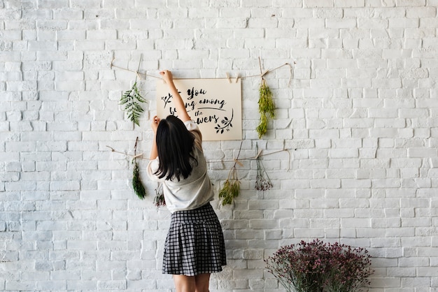 Foto gratuita una mujer decorando la pared con flores