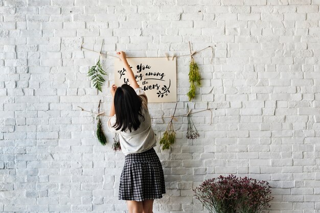 Una mujer decorando la pared con flores