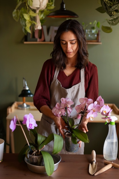 Foto gratuita mujer decorando su casa con orquídeas
