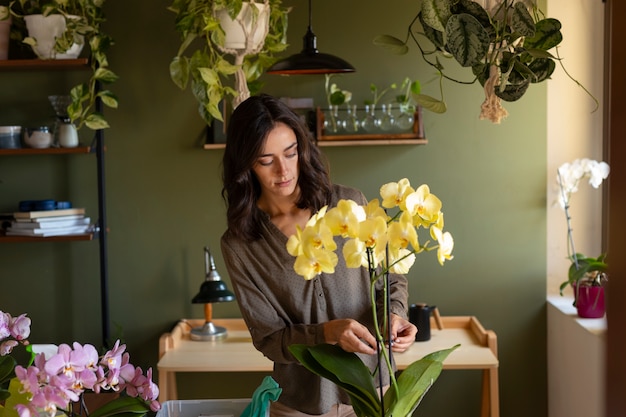 Foto gratuita mujer decorando su casa con orquídeas