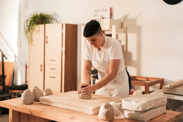 Mujer en delantal amasando la arcilla en el taller.