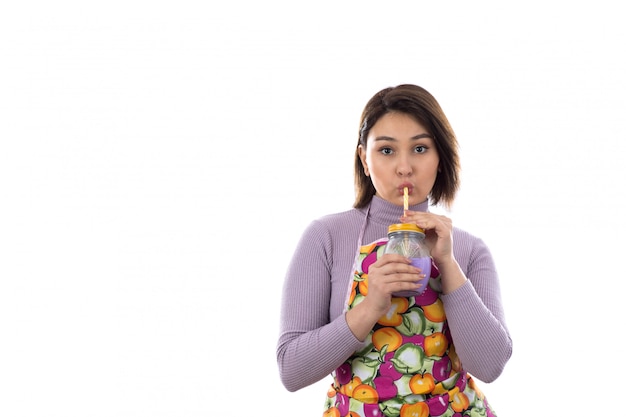 Mujer con delantal colorido beber jugo