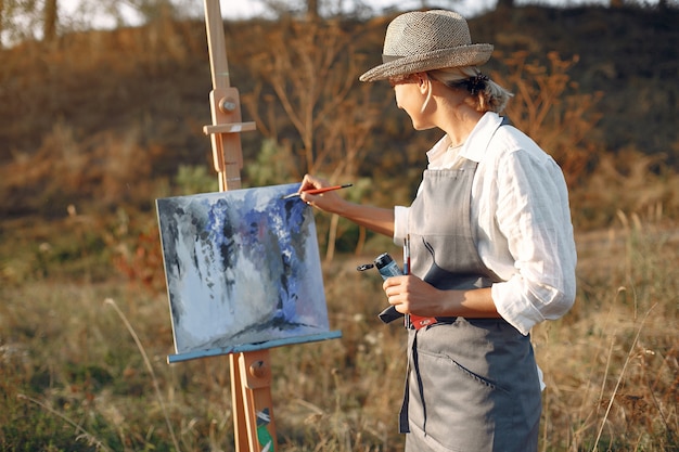 Mujer en un delantal pintando en un campo