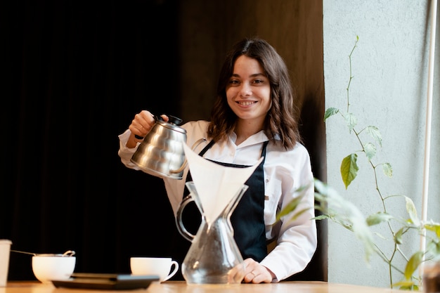 Mujer en delantal posando con cafetera