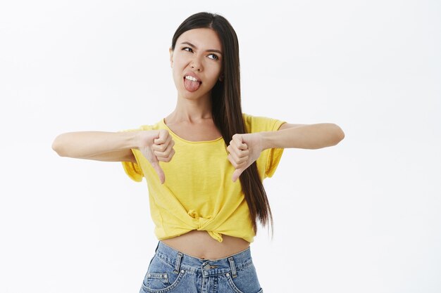 Mujer delgada bronceada con estilo inmadura y temperamental poco impresionada sin maquillaje sacando la lengua