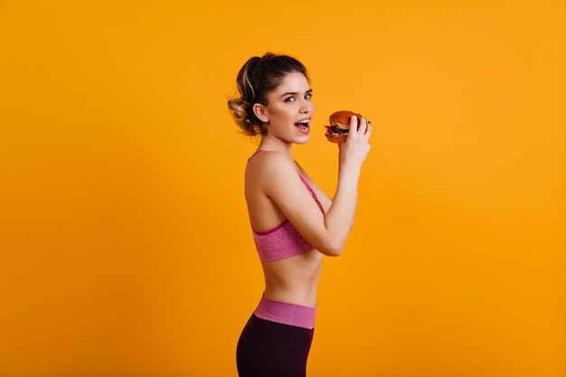 Mujer delgada comiendo hamburguesa sabrosa