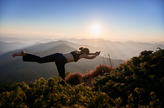 Mujer delgada haciendo ejercicio de yoga en la naturaleza