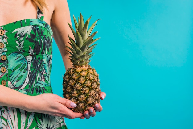 Mujer delgada joven en el vestido florecido que sostiene la piña