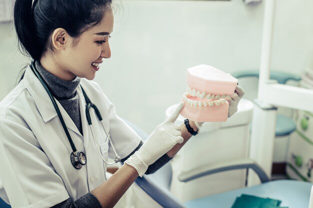 Mujer dentista explicando dientes artificiales al paciente en clínica