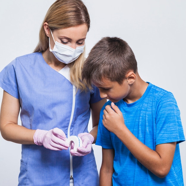 Mujer dentista mostrando dientes modelo a niño