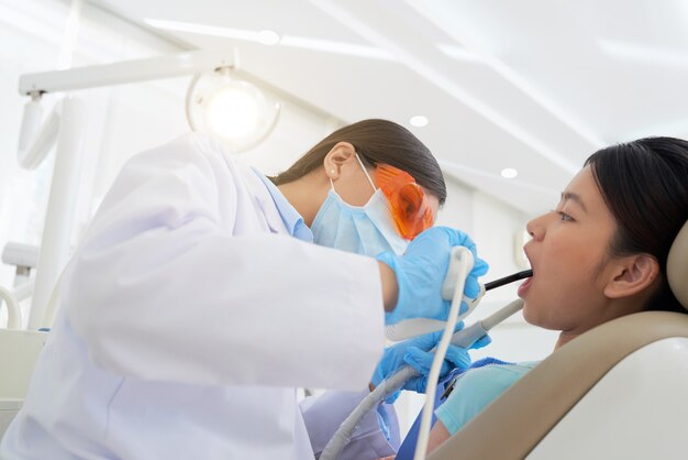 Mujer dentista tratando los dientes del paciente en clínica