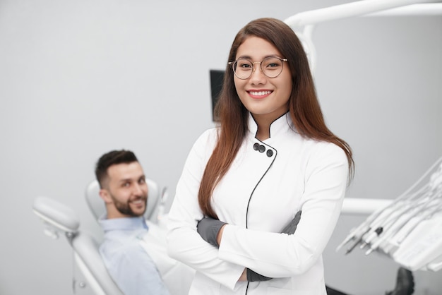 Mujer dentista en uniforme blanco mirando a la cámara y posando