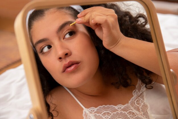 Mujer depilarse las cejas de cerca