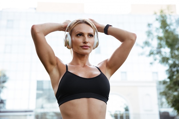 Mujer de deportes joven fuerte concentrada escuchando música