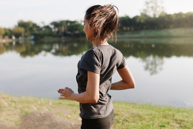 Mujer deportista corriendo con el lago de fondo