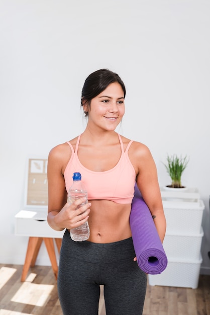 Foto gratuita mujer deportiva con alfombra de yoga