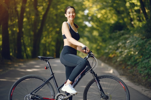 Mujer deportiva andar en bicicleta en el bosque de verano