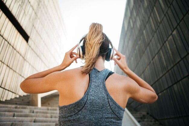 Mujer deportiva con auriculares en entorno urbano