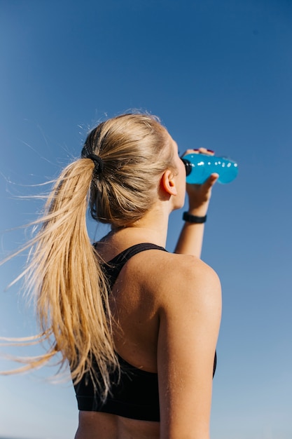 Foto gratuita mujer deportiva bebiendo en la playa