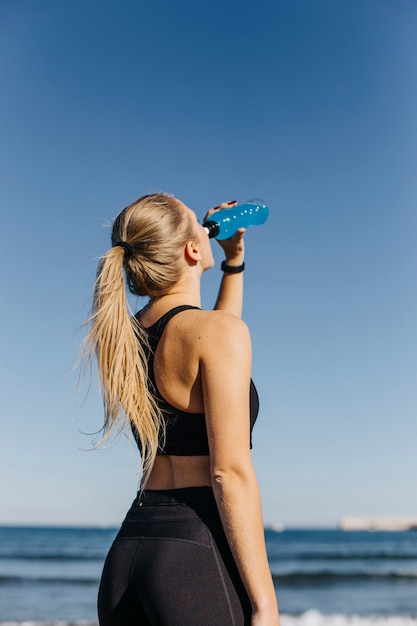 Mujer deportiva bebiendo en la playa