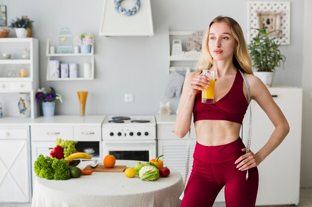 Mujer deportiva en cocina con zumo sano