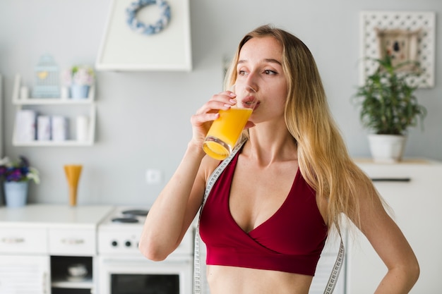 Mujer deportiva en cocina con zumo sano