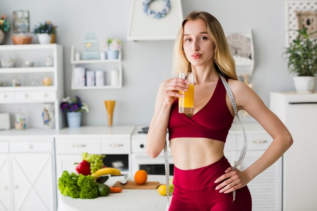 Mujer deportiva en cocina con zumo sano