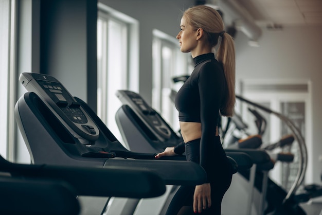 Mujer deportiva corriendo en cinta rodante en el gimnasio