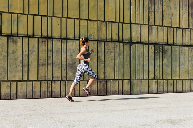 Mujer deportiva corriendo en entorno urbano