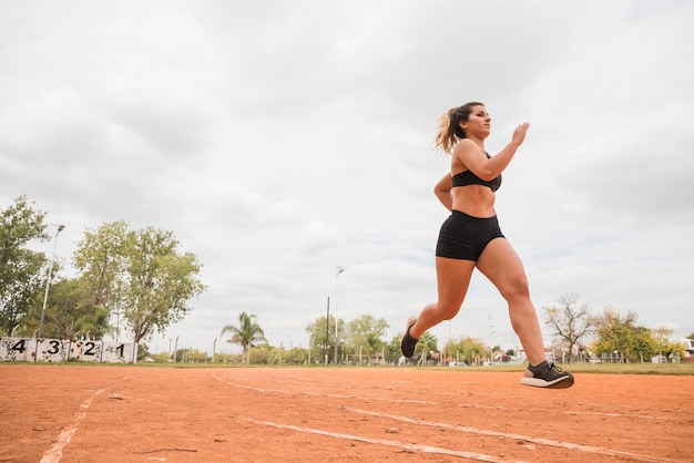 Mujer deportiva corriendo en pista de estadio