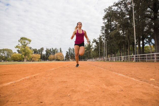 Mujer deportiva corriendo en pista de estadio