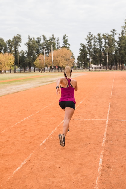 Mujer deportiva corriendo en pista de estadio