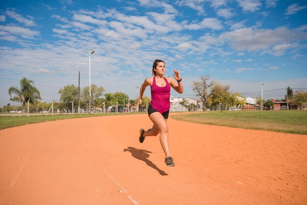 Mujer deportiva corriendo en pista de estadio