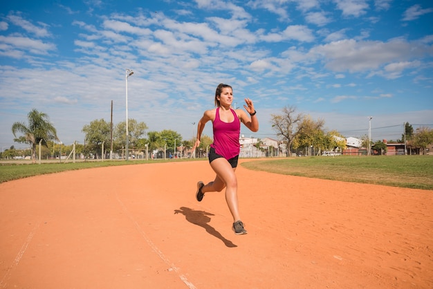 Mujer deportiva corriendo en pista de estadio