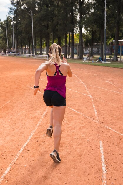 Mujer deportiva corriendo en pista de estadio