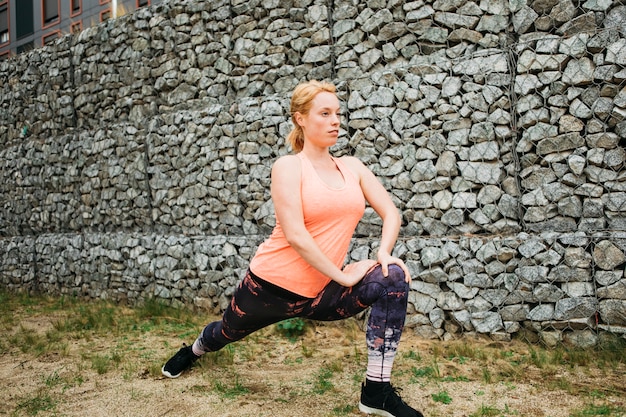 Mujer deportiva estirando en entorno urbano