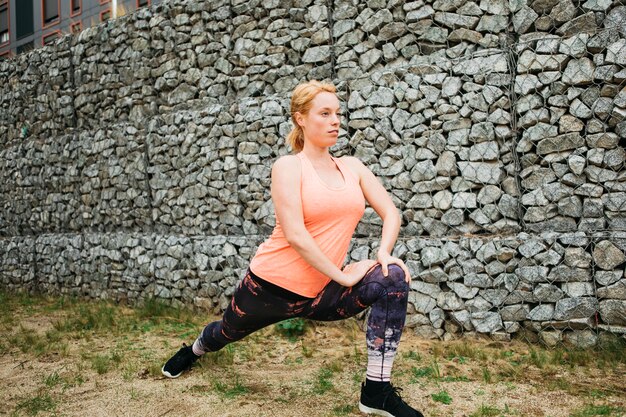 Mujer deportiva estirando en entorno urbano