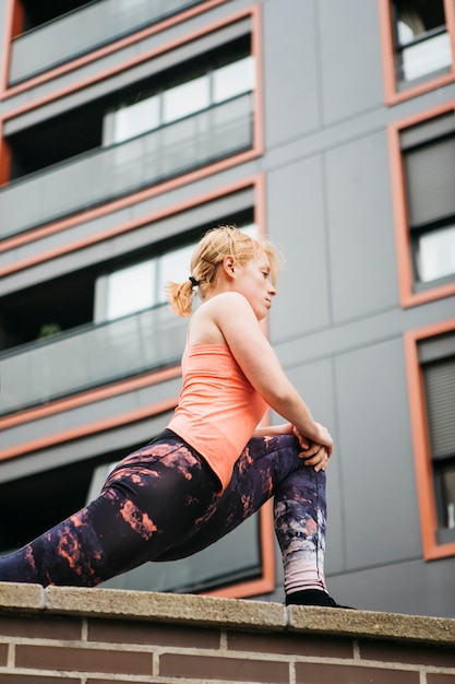 Mujer deportiva estirando en entorno urbano