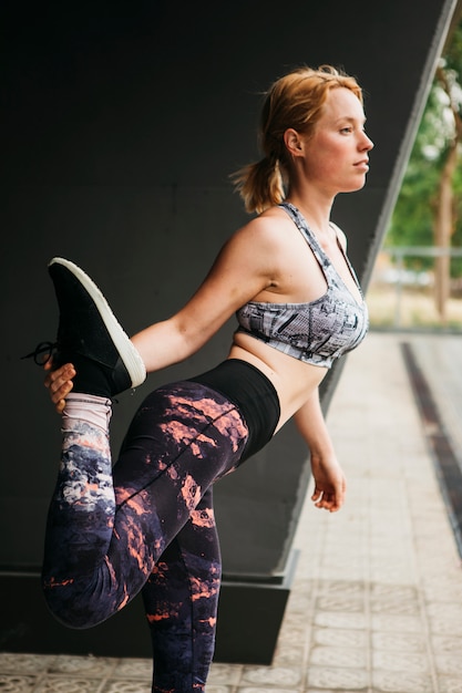 Mujer deportiva estirando en entorno urbano