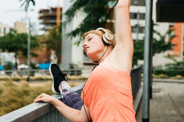 Mujer deportiva estirando en entorno urbano