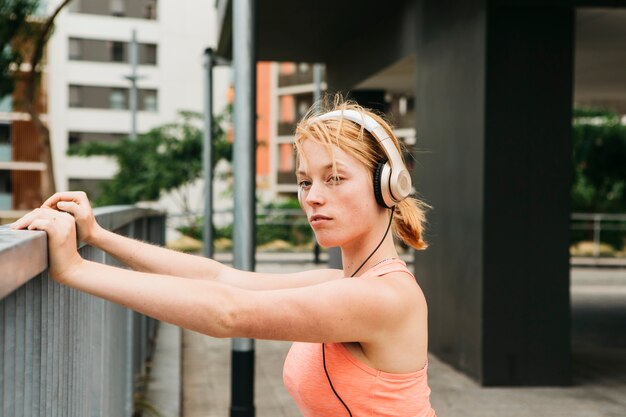 Mujer deportiva estirando en entorno urbano